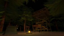 A view of a wooden watchtower with a tent and campfire below on the ground.